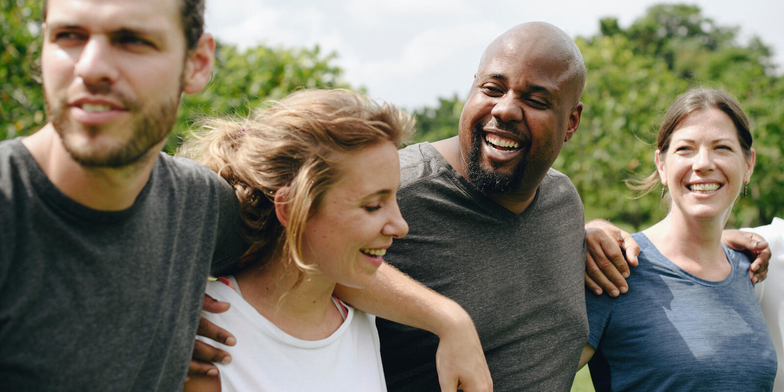 Two women and two men on a field laughing, walking and holding one another