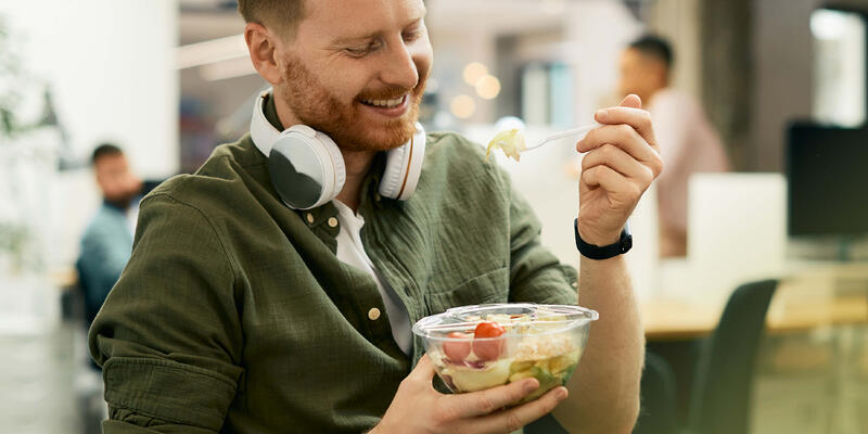 A white man eating salad from a bowl