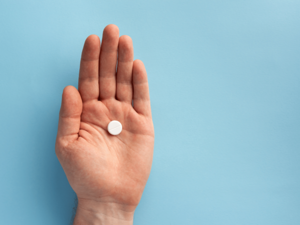 A hand holding a white colour contraceptive pill
